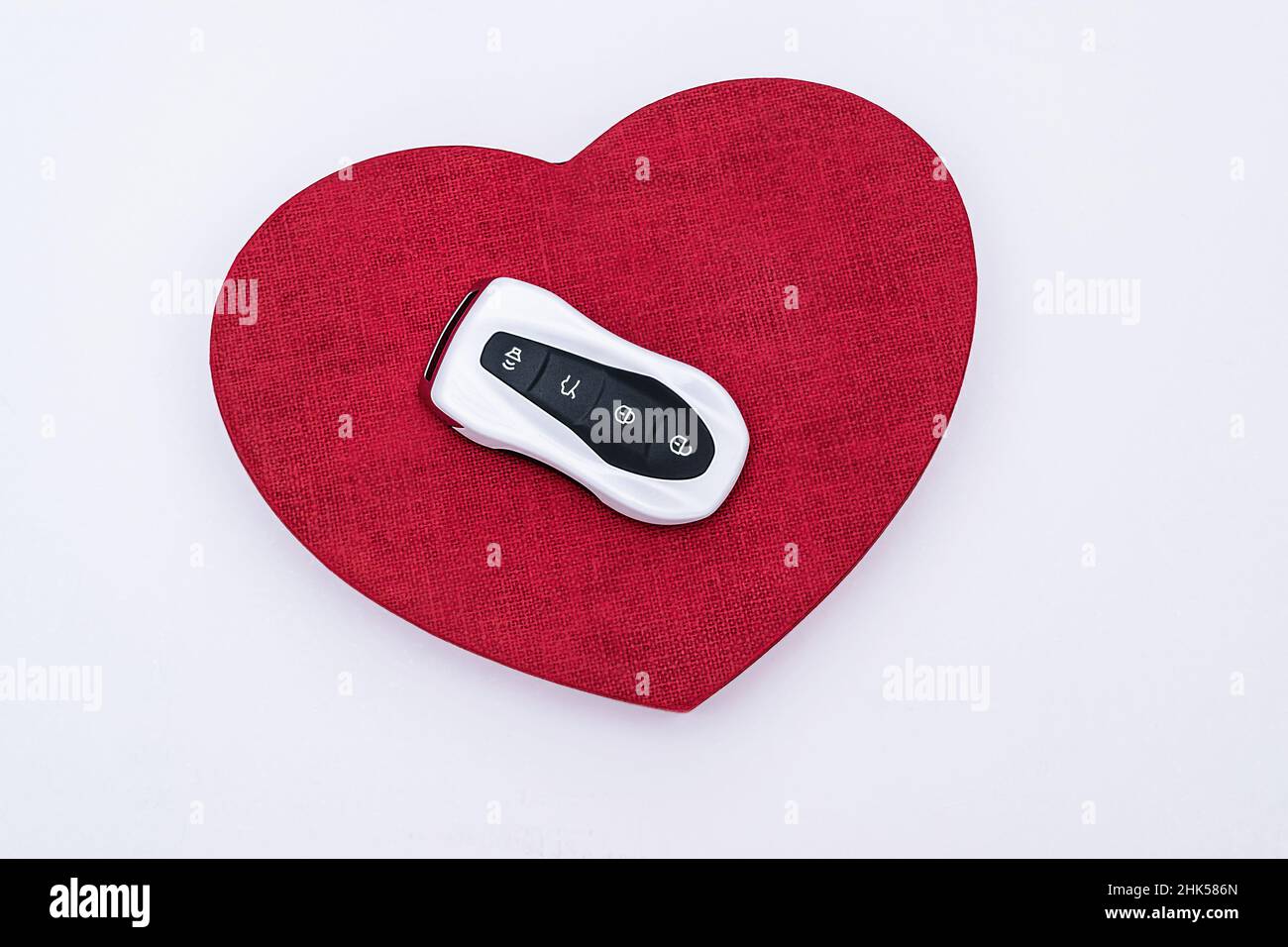 Flat lay concept and gift idea. Smart car key on a red embossed heart in the middle of a white background. Electronics, spare parts and car accessorie Stock Photo