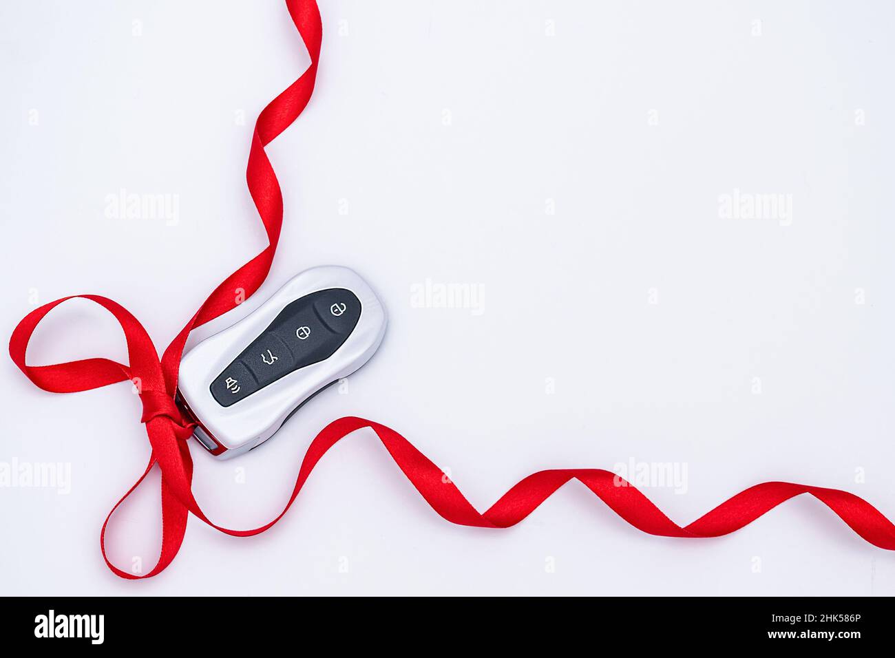 Flat lay smart car key with a red gift ribbon on a white background. Electronics, spare parts and car accessories. Concept and gift idea. Horizontal p Stock Photo