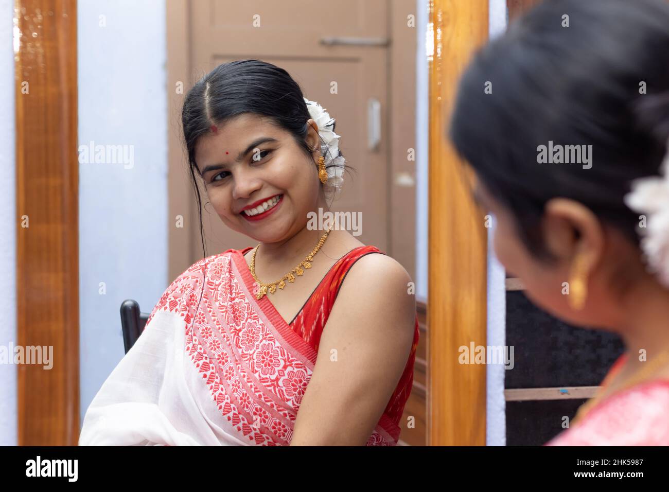 An Indian married woman in red saree looking into the mirror with smiling  face Stock Photo - Alamy