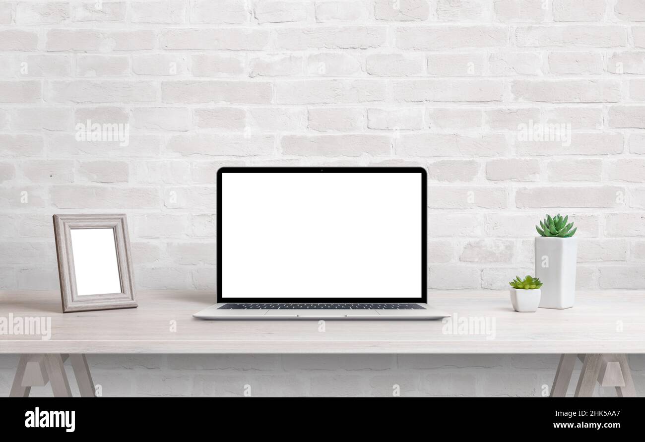 Laptop mockup on work desk. Work at home concept. Clean desk with photo frame and plants Stock Photo