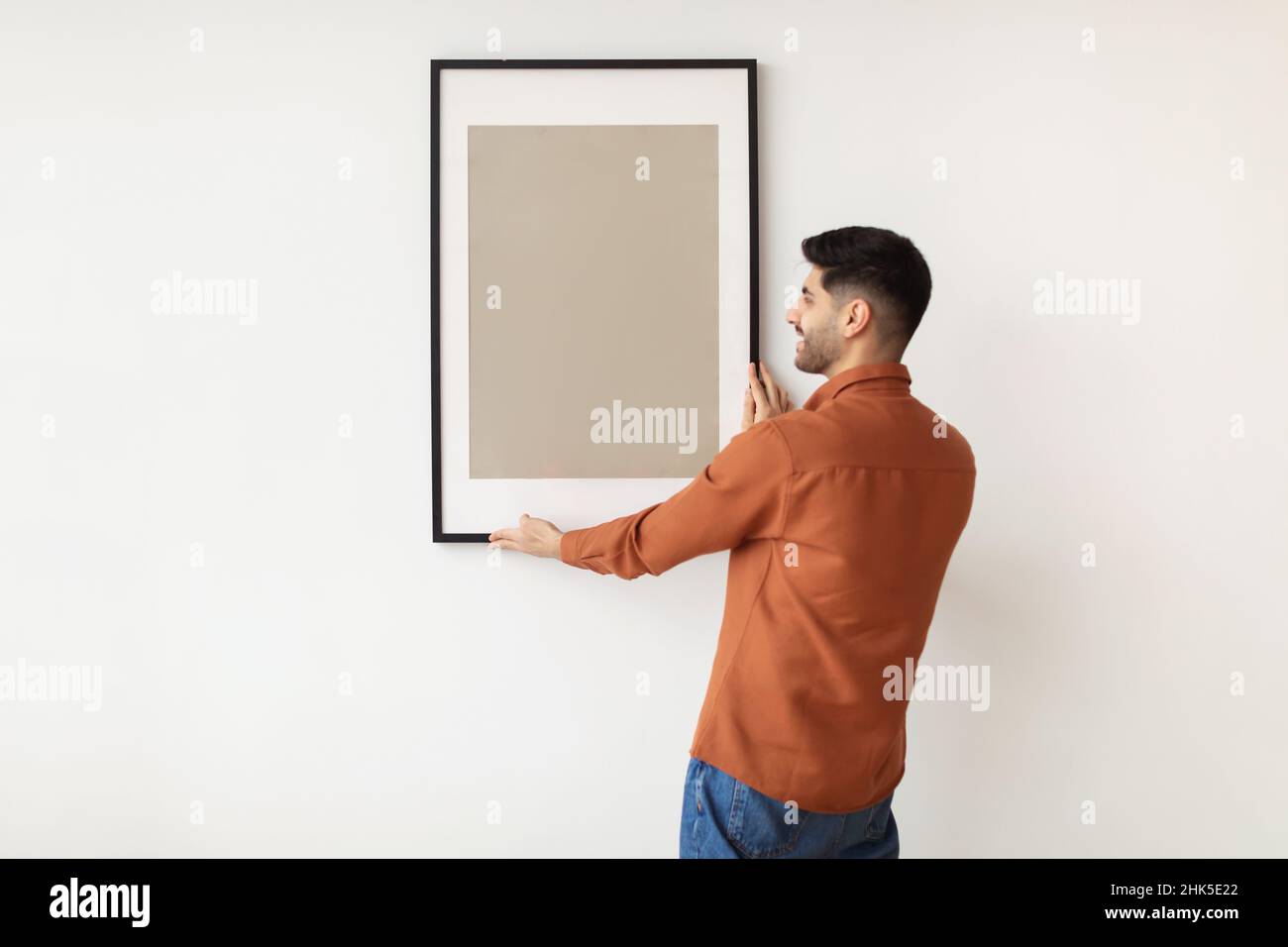 Young man hanging picture frame on the wall Stock Photo Alamy