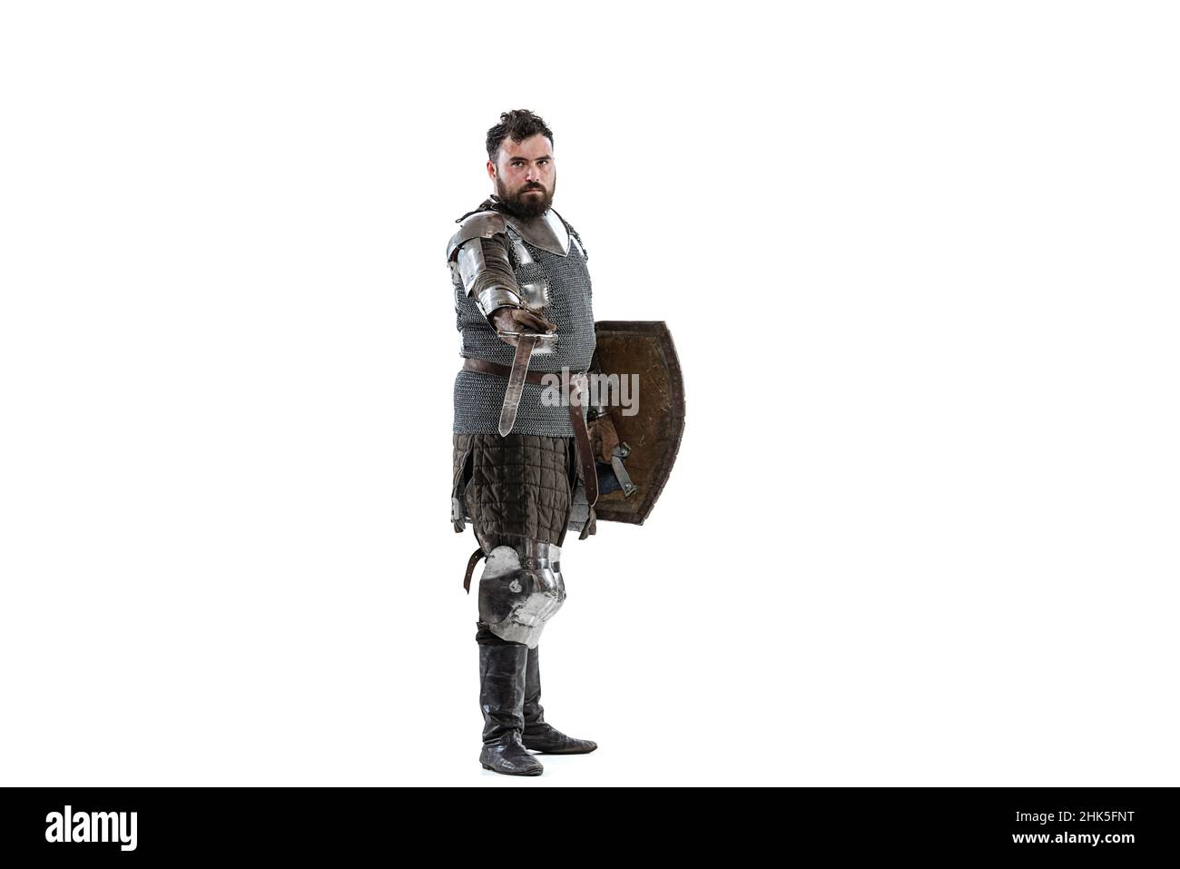 Portrait of seriuos man, medieval warrior or knight with sword and shield in special chain armour isolated over white background Stock Photo