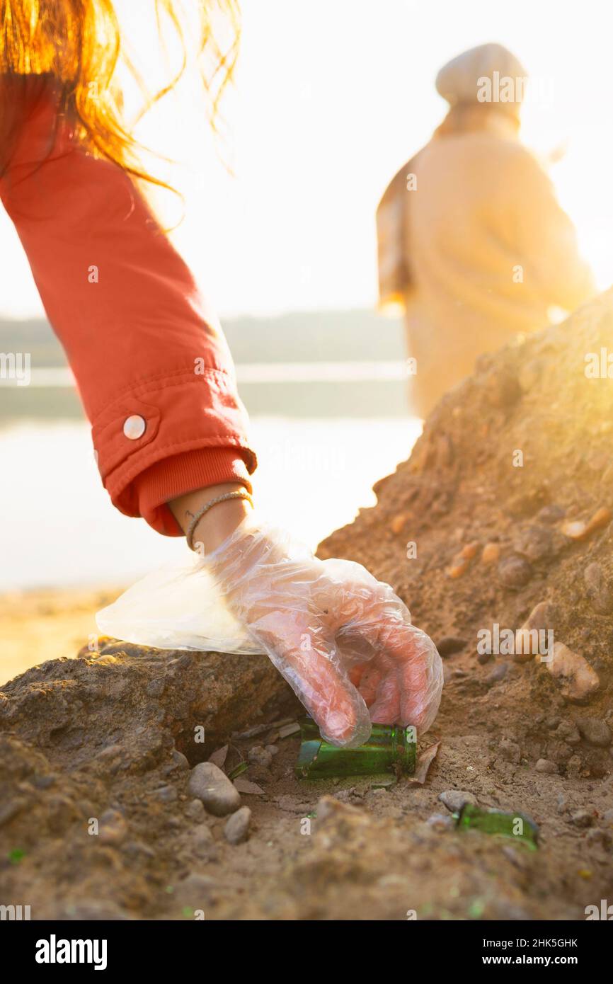 Detail of a person cleaning a beach from glass bottles Stock Photo