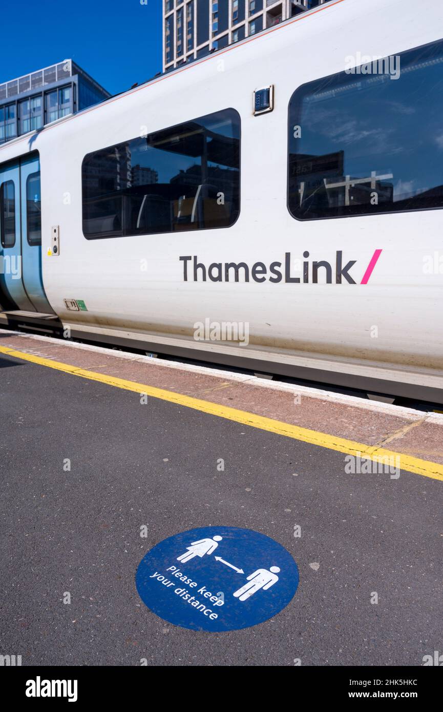 Class 700 Desiro City train in Thameslink livery in a railway station in the UK, with social distance markings shown on the platform. Stock Photo