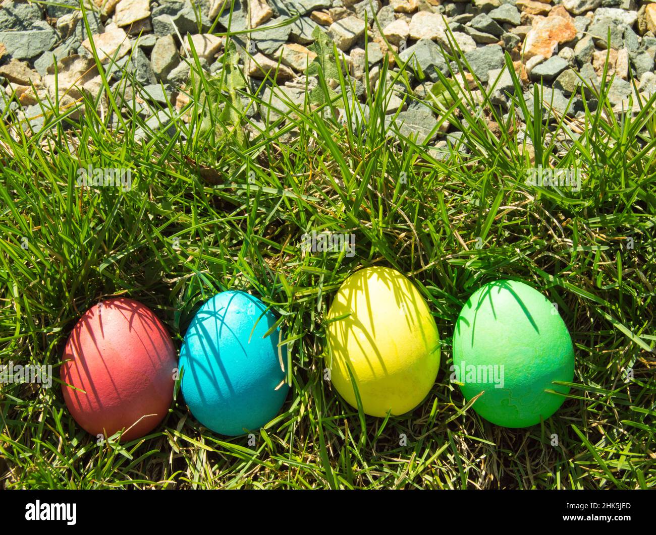 Four painted and decorative Easter eggs in the grass. Top view, copy space. Stock Photo