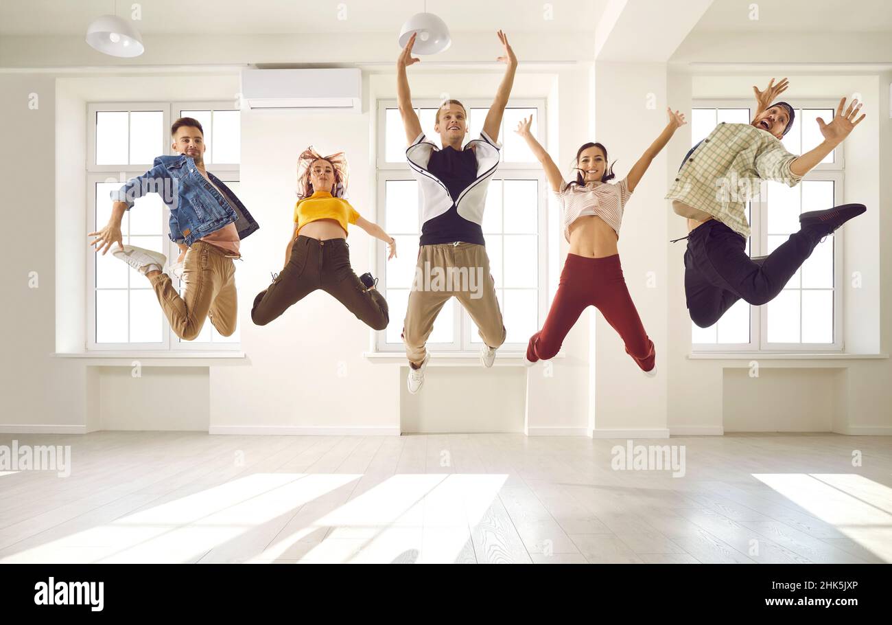 Group of happy energetic contemporary dancers having fun and jumping up in the air Stock Photo