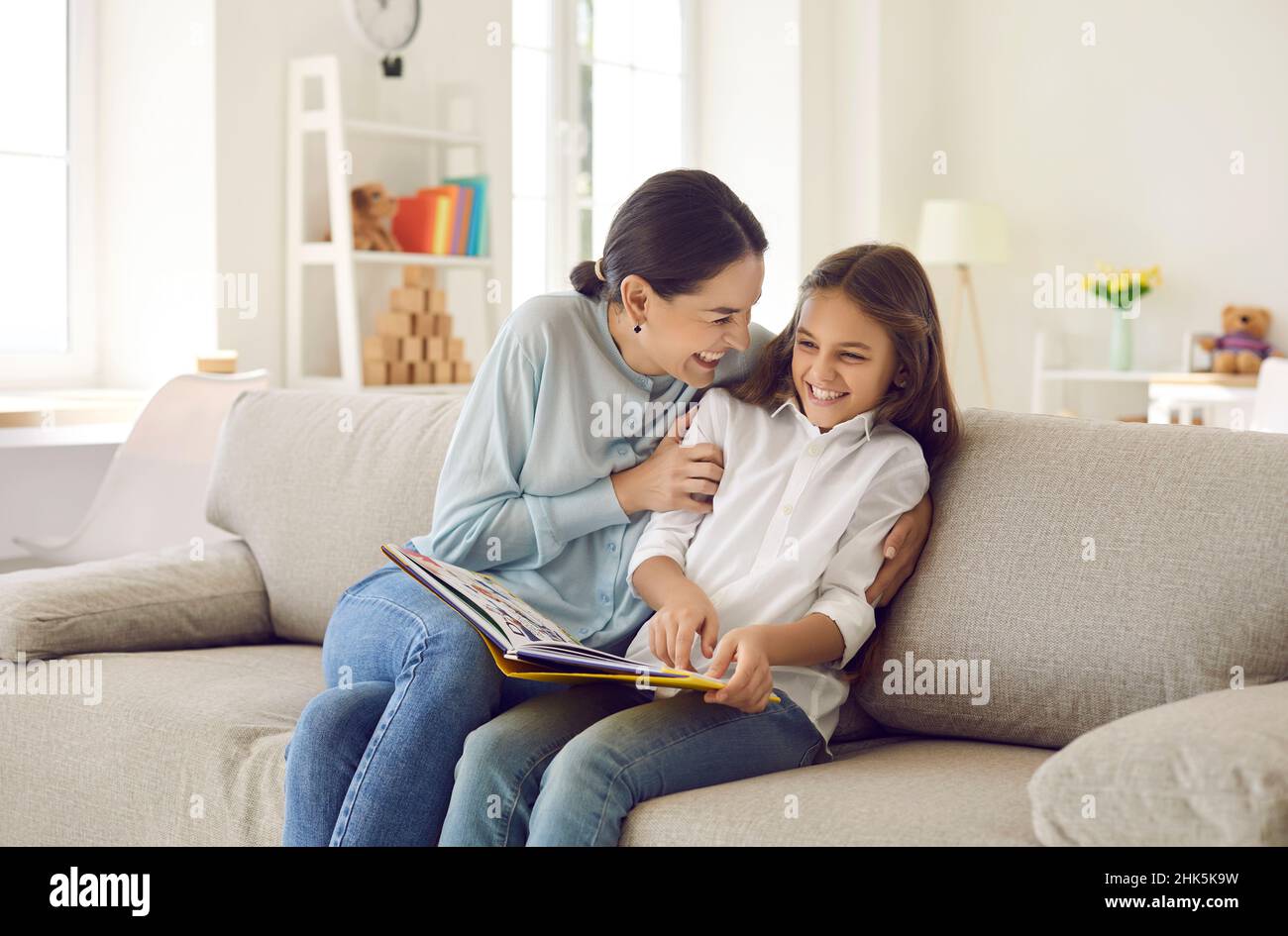 Smiling mom and teen daughter reading book Stock Photo