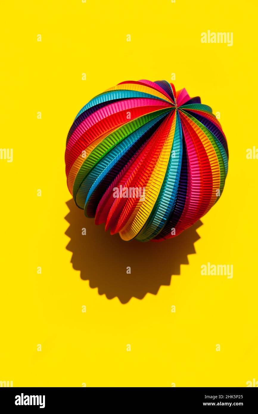 Sphere with a rainbow pattern on a bright yellow background, top view, close-up. Stock Photo
