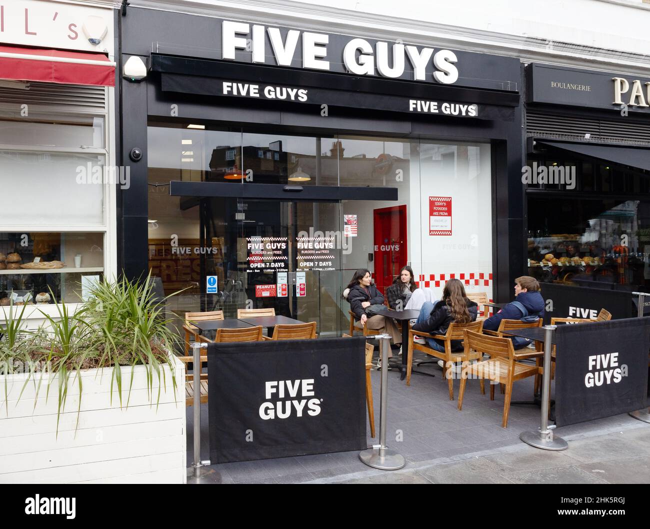 Five Guys UK; People eating outside a Five Guys restaurant, an american food chain with restaurants across the UK, South Kensington, London UK Stock Photo