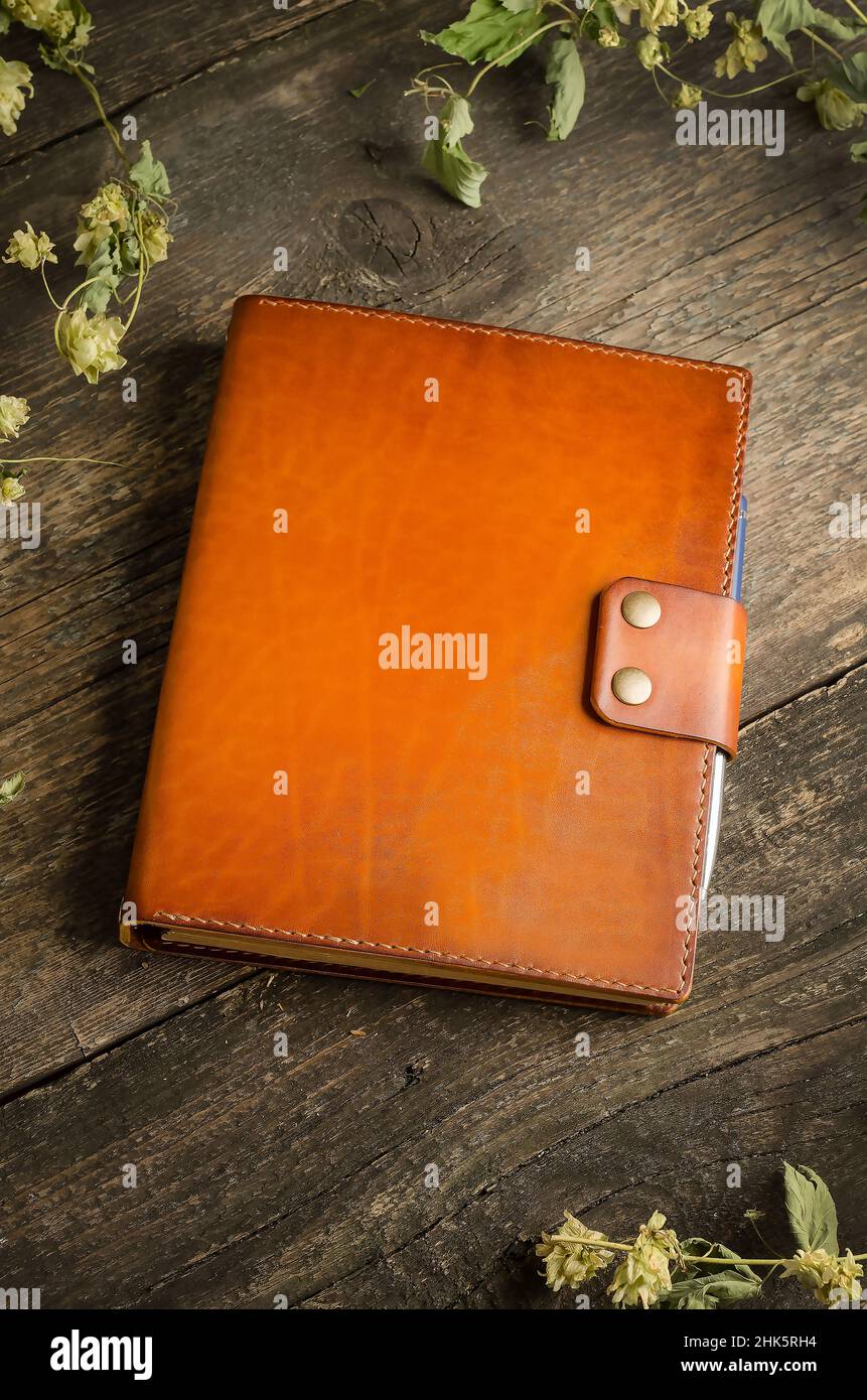 Handmade leather men's wallet in brown-orange color on an old vintage wooden background. Stock Photo