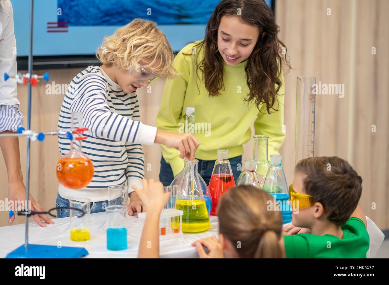 Boy lowering pipette into flask and children watching Stock Photo