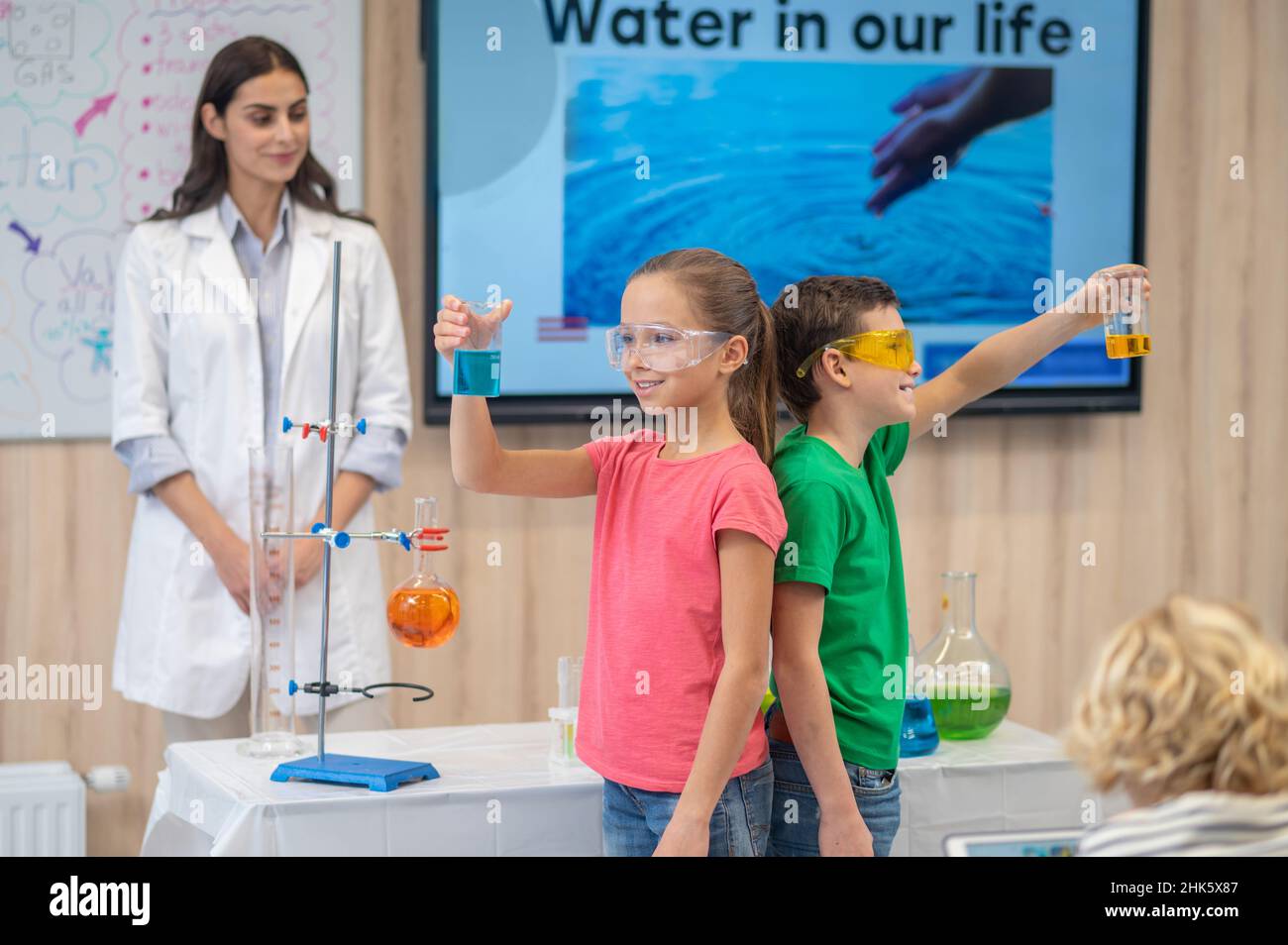 Boy and girl standing back to back holding beakers Stock Photo