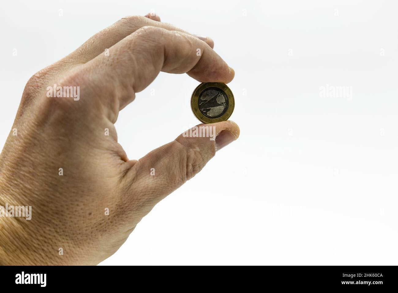 A hand holding a euro coin on white background Stock Photo - Alamy
