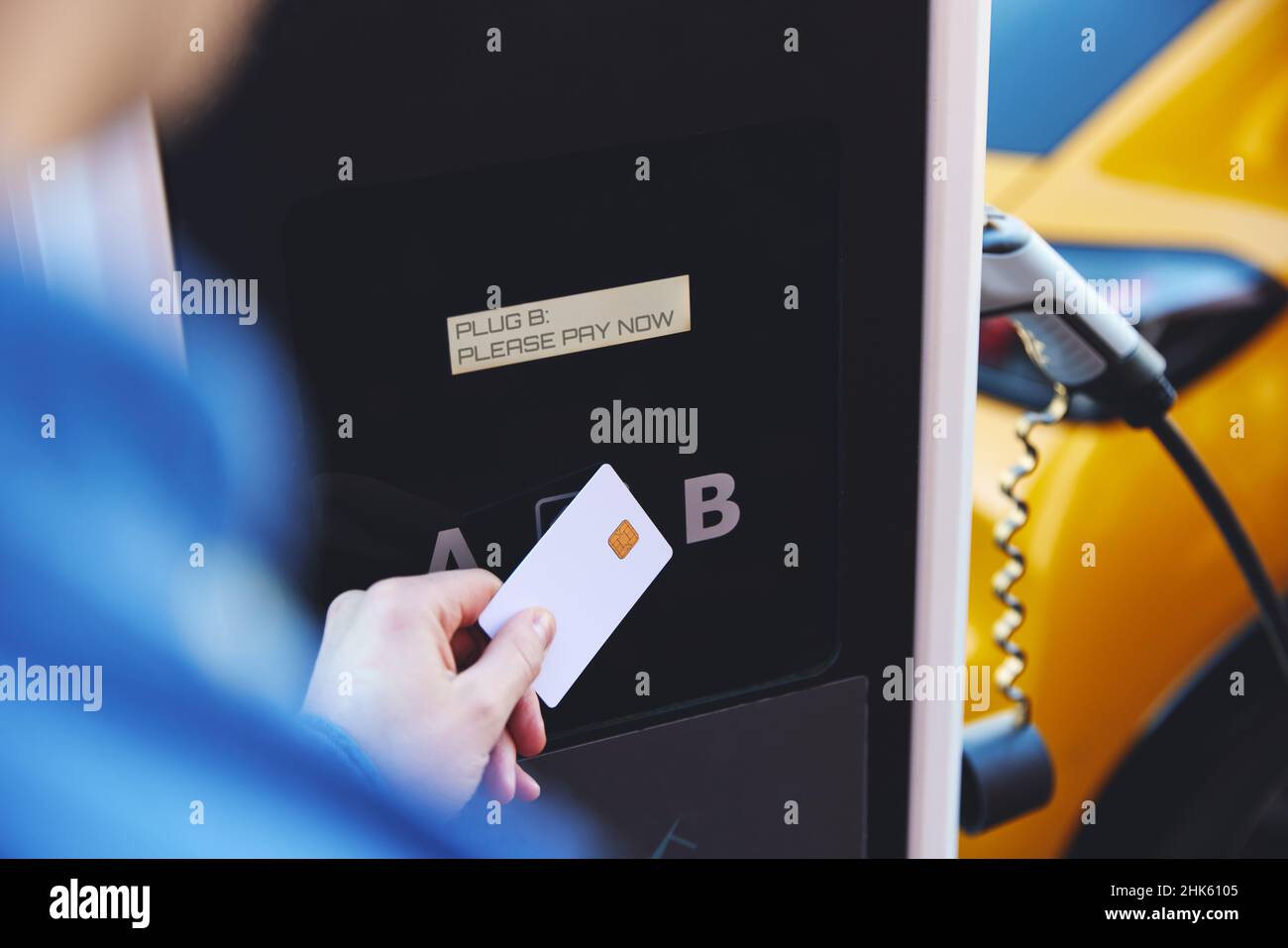 Man Charging Electric Vehicle Paying For Energy With Credit Card At