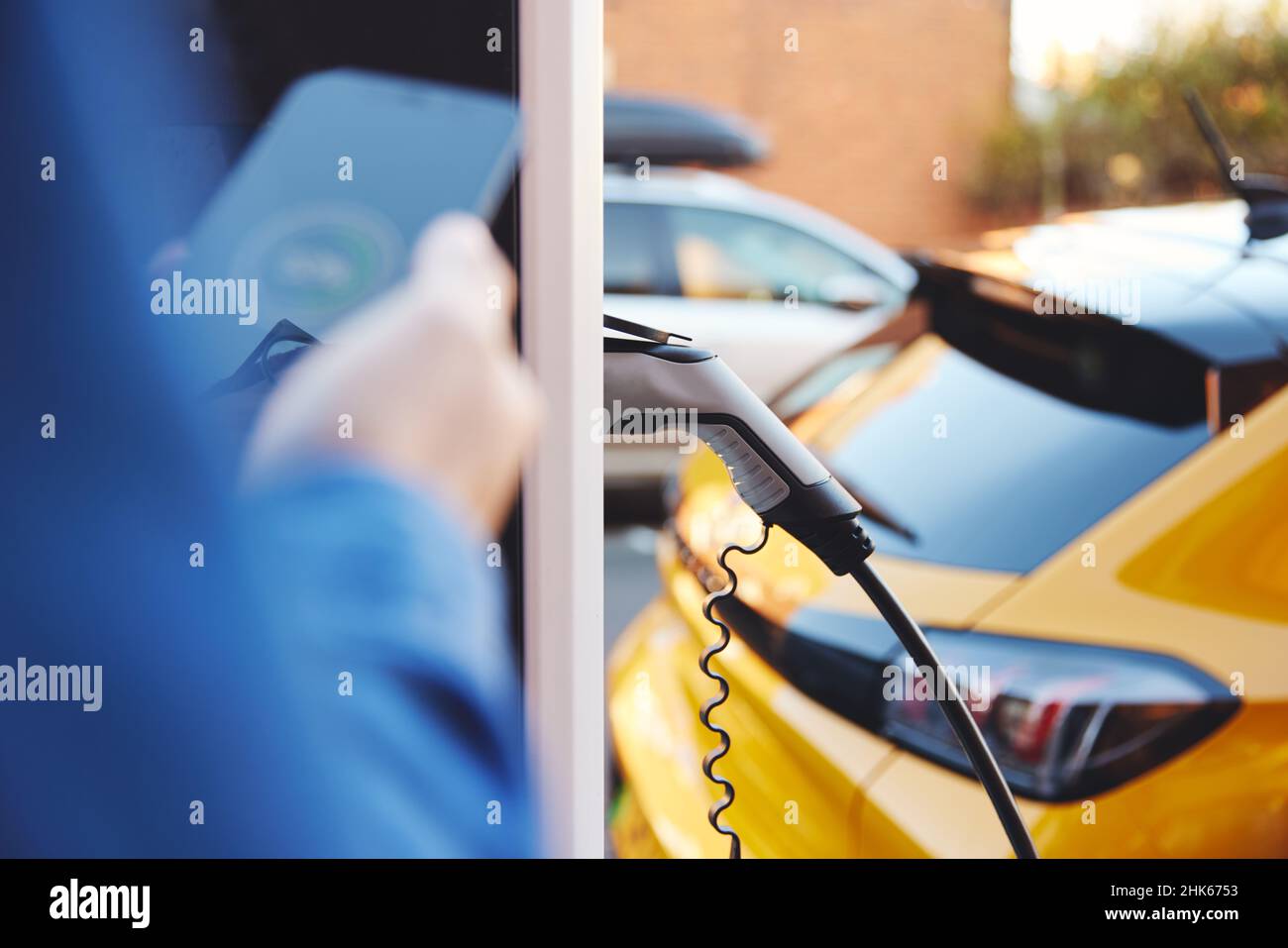 Electric car plugged in on street with smart phone app Stock Photo Alamy