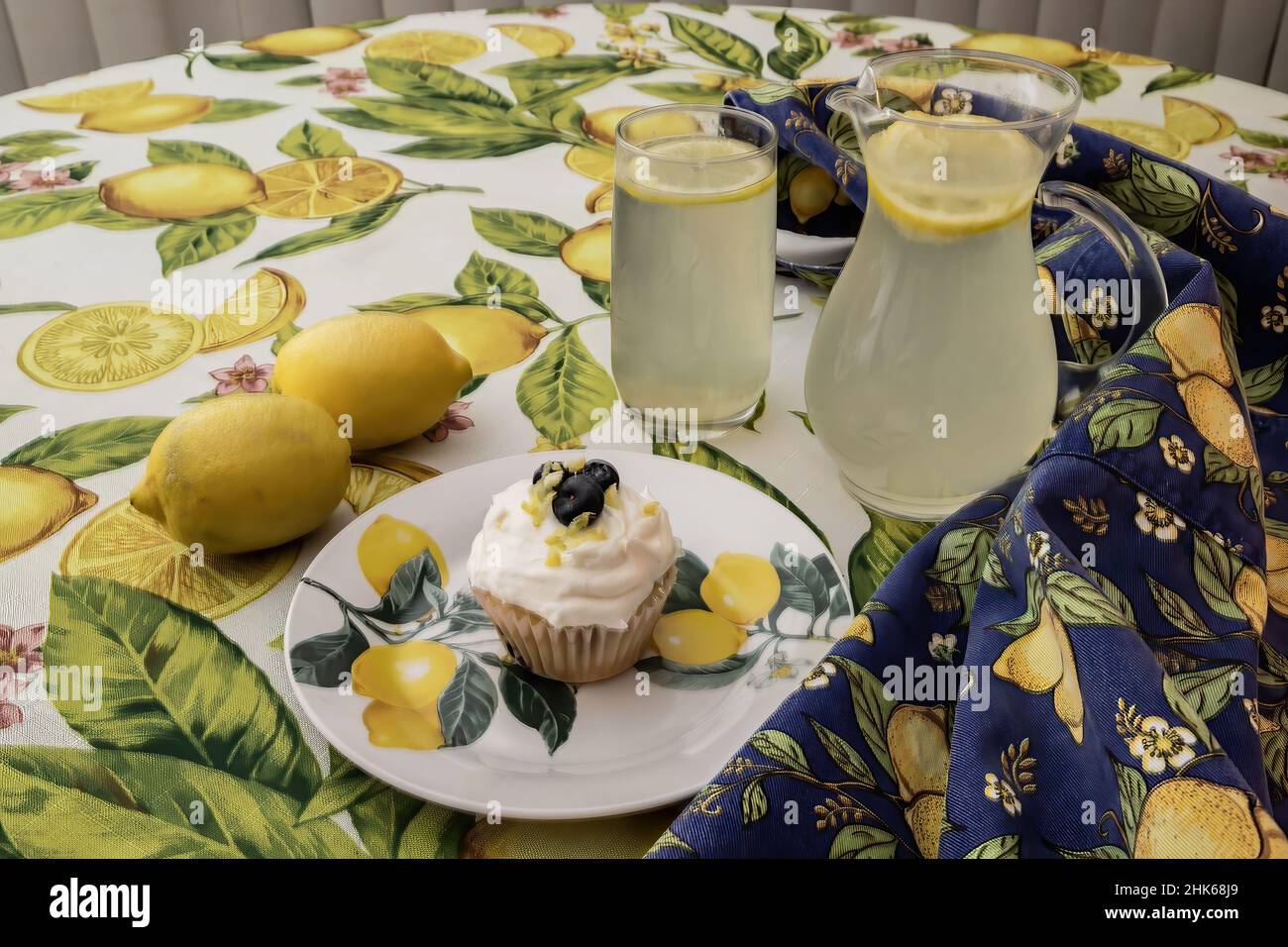 Lemon blueberry cupcake with blueberries and lemon zest with lemons and lemonade on decorative plate and tablecloths. Stock Photo