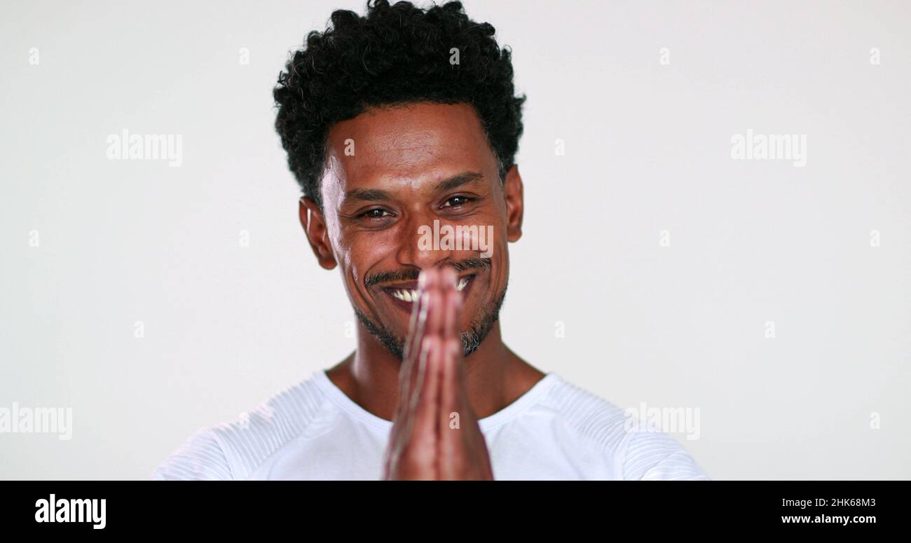 Happy charismatic handsome black guy smiling to camera giving faith sign with hands, feeling compassionate Stock Photo