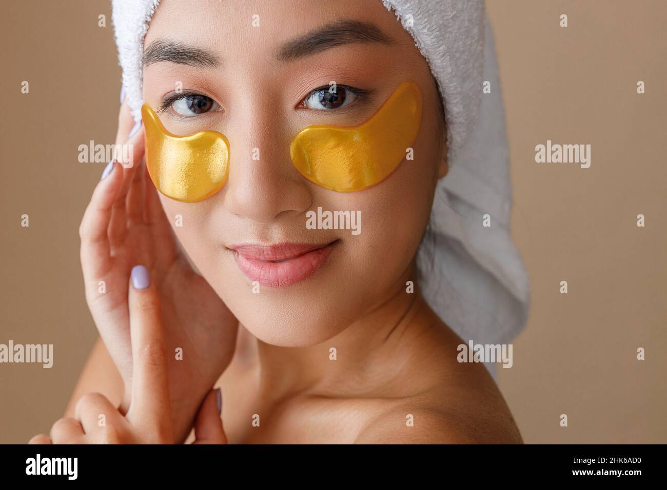 Smiling young woman using gold undereye patches Stock Photo Alamy