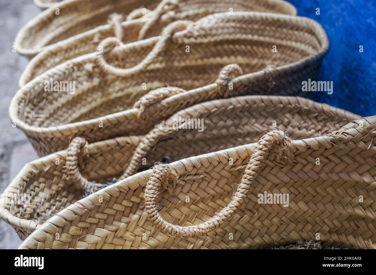 A row of wicker baskets against a blue wall in a Moroccan market Stock