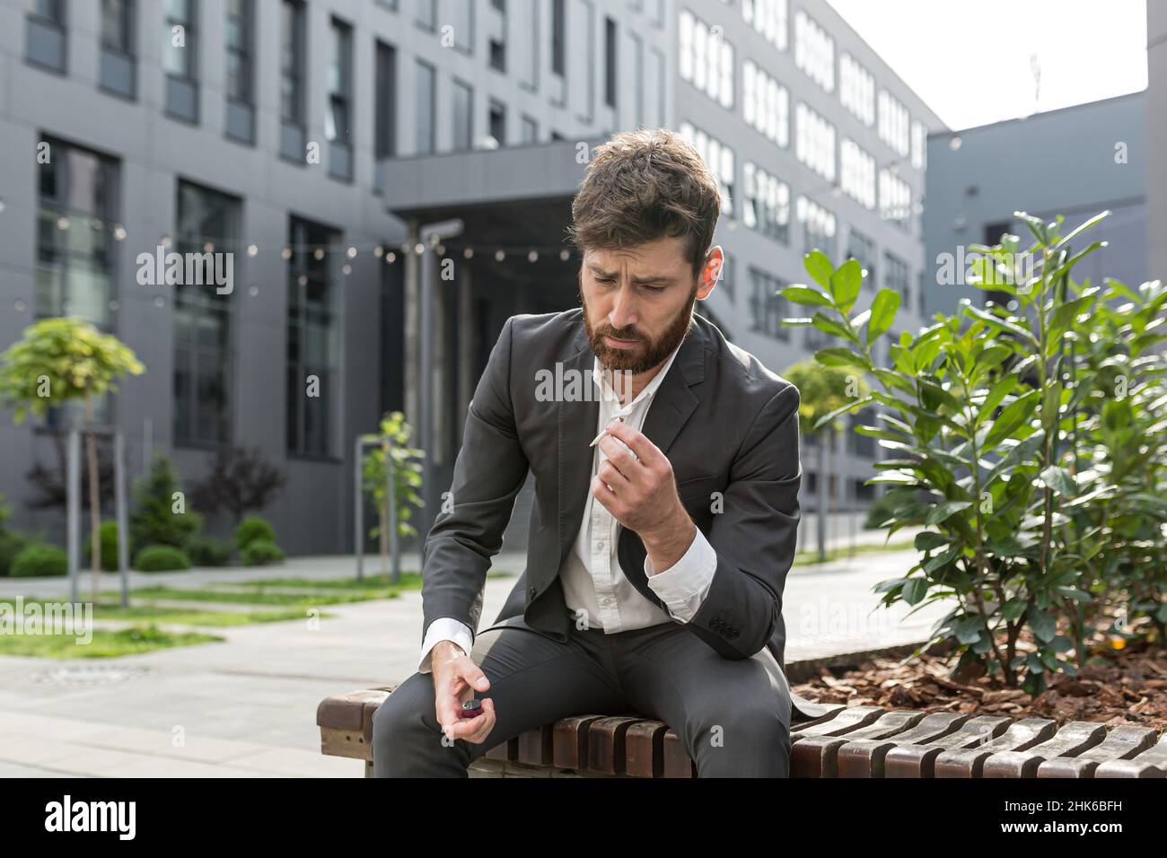 businessman smoking cigarette Male businessman smoking cigarette in the air near the office relieves  stress after a hard day's work, tired reworked depressed Stock Photo