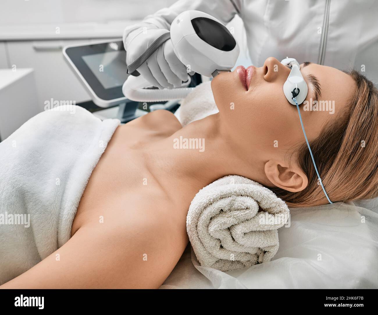 Photorejuvenation, rosacea treatment, removing brown spots and vascular mesh. Cosmetologist using IPL apparatus treats skin of female patient's face Stock Photo