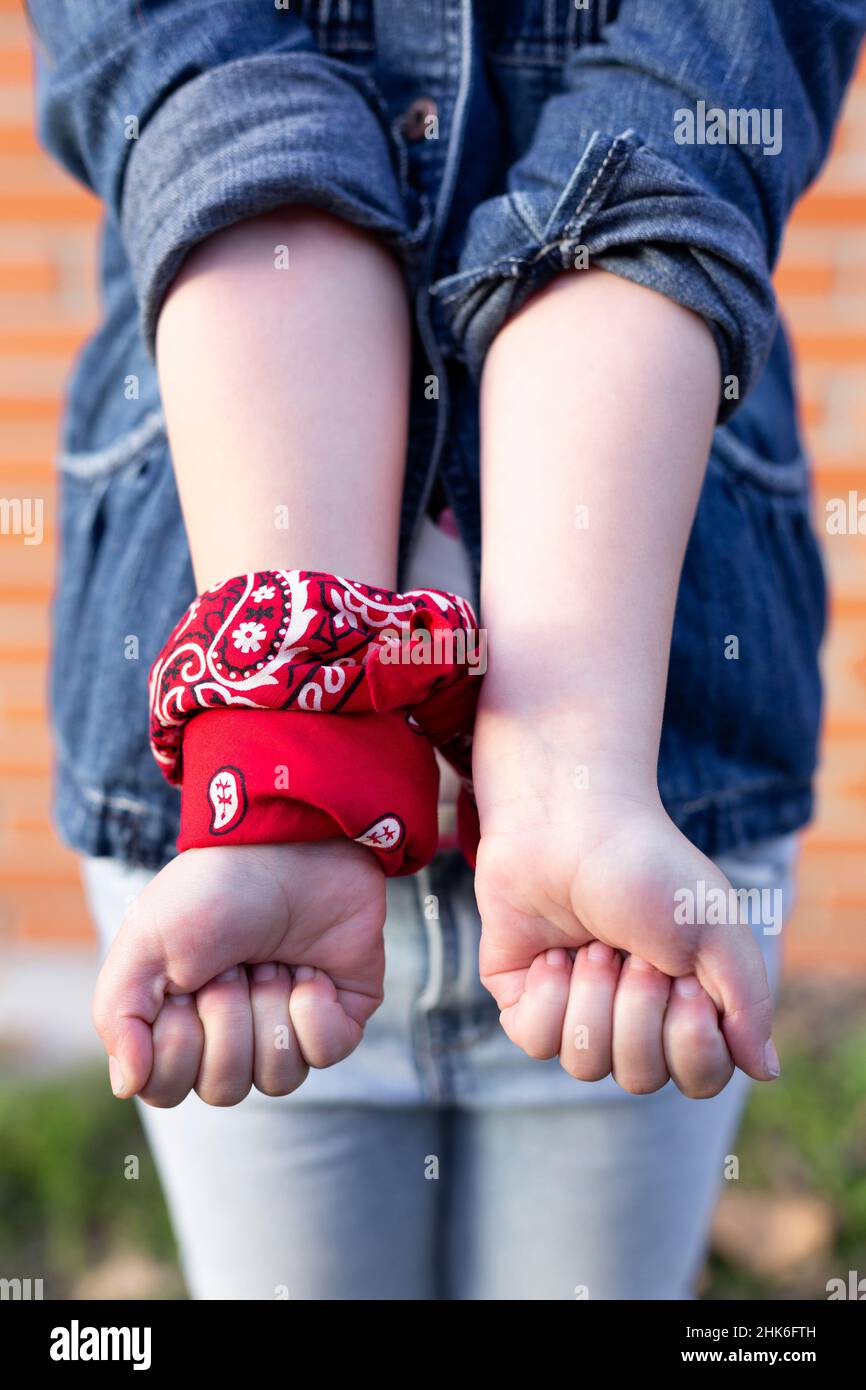 Detail of the arms of an unrecognizable person with a red scarf tied over one of the wrists. Concept of feminism, equality and fight. Stock Photo