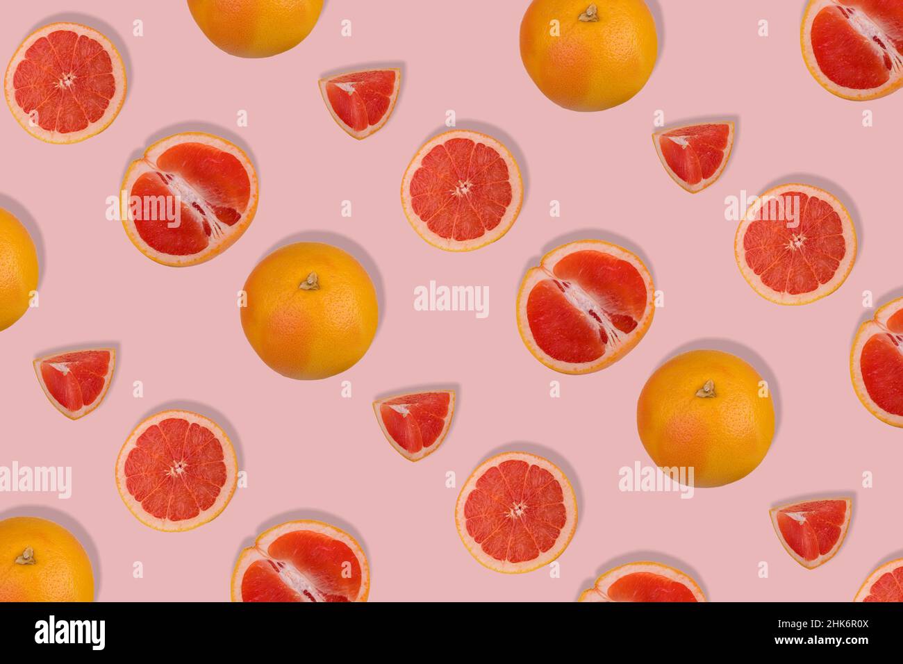 Creative pattern with fresh whole and sliced grapefruit on bright pink background. Minimal fruit concept. Vitamins, healthy diet concept.  Flat lay. Stock Photo