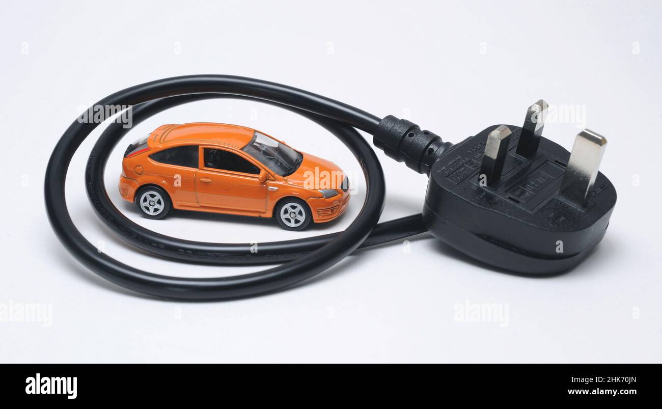 MODEL CAR WITH ELECTRIC PLUG AND LEAD RE ELECTRIC VEHICLES EV EV'S DIESEL PETROL FOSSIL FUEL GREEN THE ENVIRONMENT HYBRID BATTERY POWERED CARS  ETC UK Stock Photo