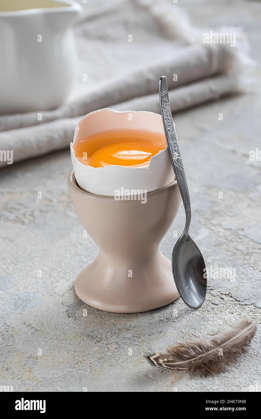 Fresh broken soft boiled egg on a stand up on white concrete rustic background. Soft eggs, healthy breakfast. Still life breakfast. Stock Photo