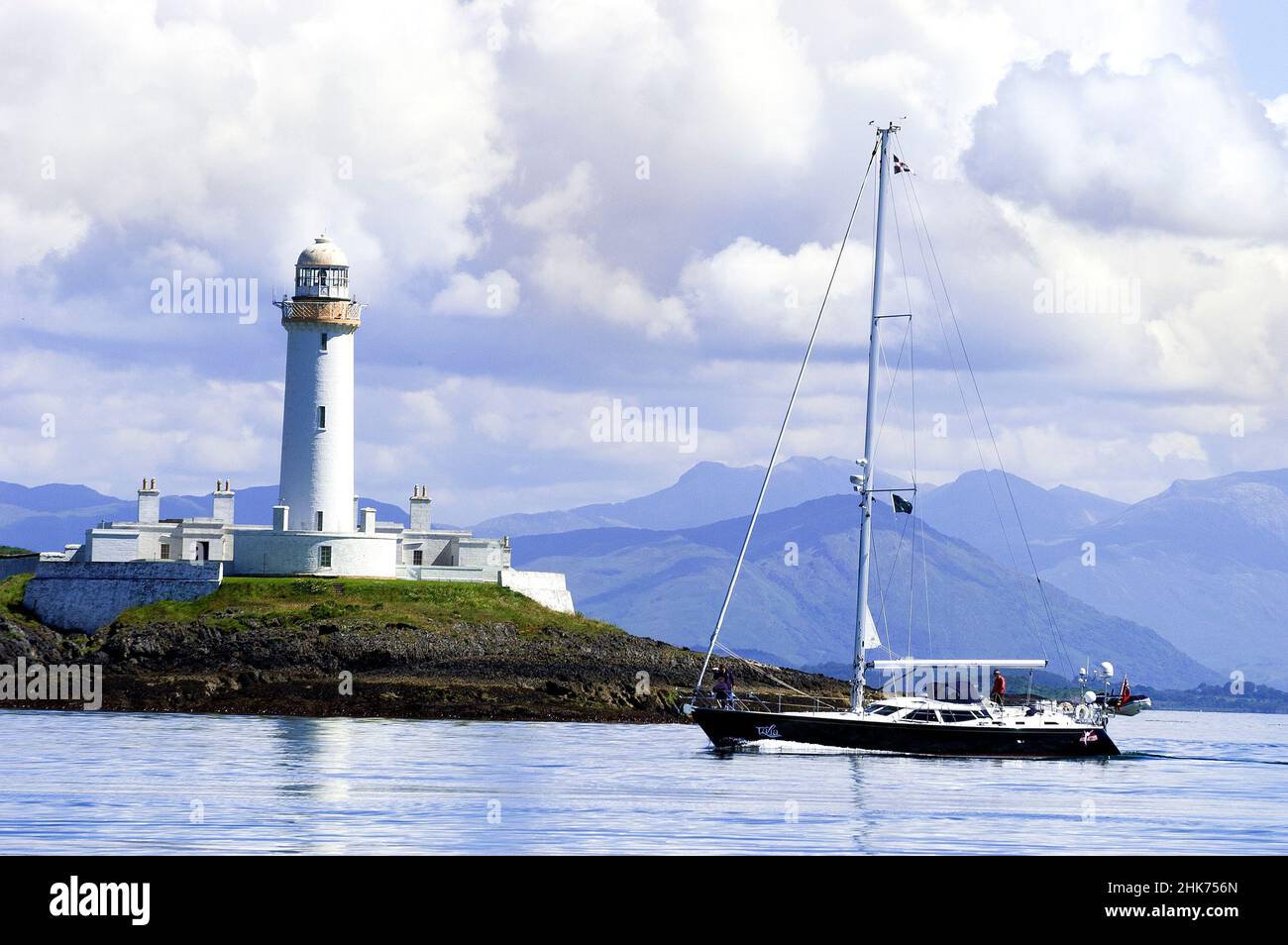 Yacht passing Lismore Lighthouse on Eilean Musdile Islet, in the Firth of Lorne at the entrance to Loch Linnhe,Argyll and Bute, Scotland, UK, Europe Stock Photo