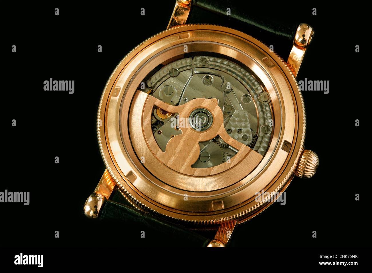 Back of luxury Swiss fashion wrist watch interior mechanism with gears and cogs. Watch With Golden Gearwheels Gears. Vintage movement mechanics. Close Stock Photo