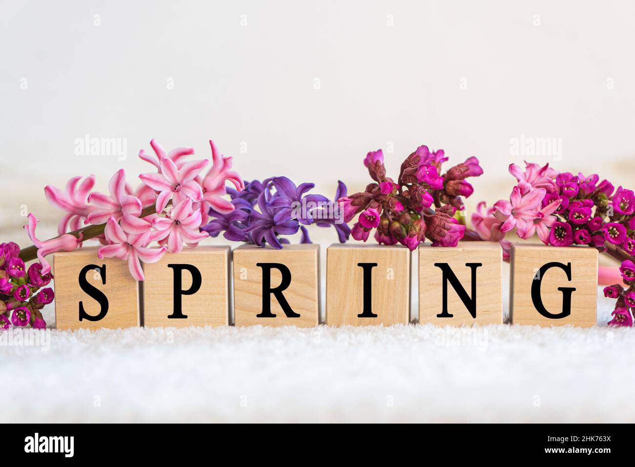 Wooden cubes with word SPRING and fresh flowers on white background ...