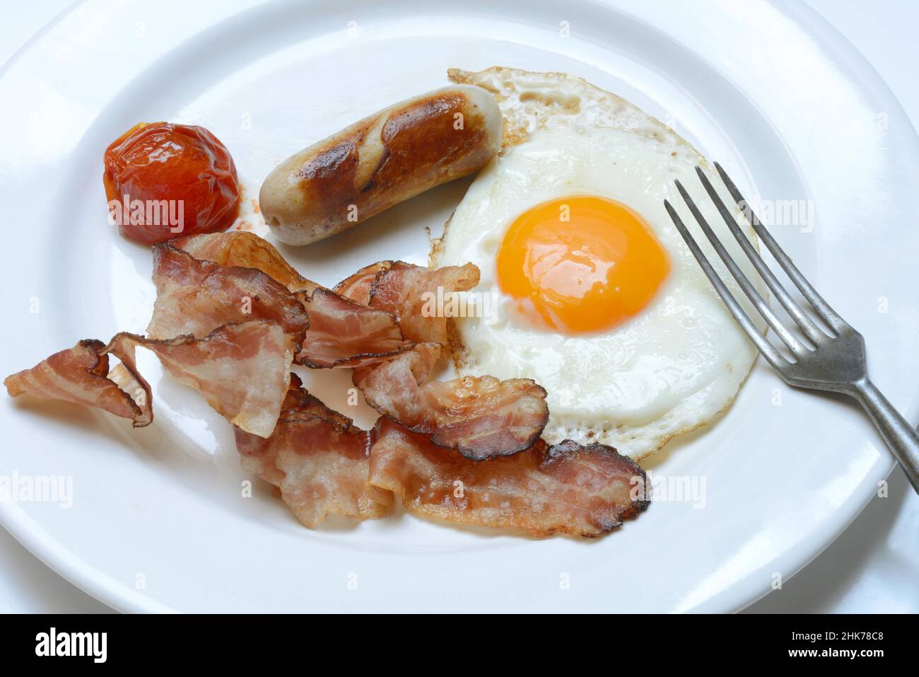 Fried egg, fried bacon and sausages on plate Stock Photo