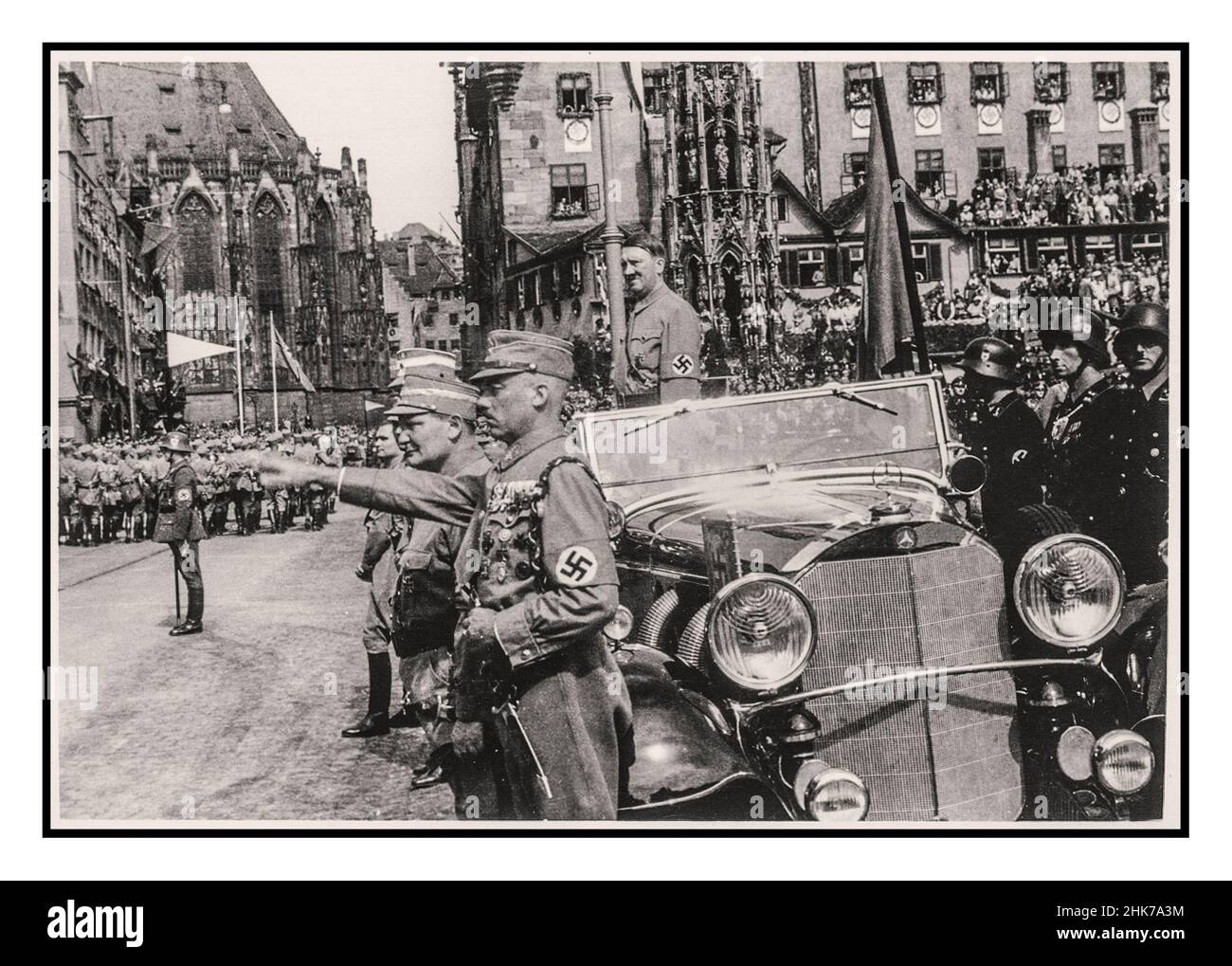 Adolf Hitler standing in his open top Mercedes car at Nuremberg Rally 1935, Germany - SA Sturmabteilung political militia troops of the Nazi party, march past Adolf Hitler during a parade in the city. 1930’s Adolf Hitler wearing swastika armband in military parade, standing in Mercedes open car with Heil Hitler salute to passing marching Sturmabteilung troops Hermann Goring in foreground Nuremberg Germany Goring and Hess are seen in the foreground Stock Photo