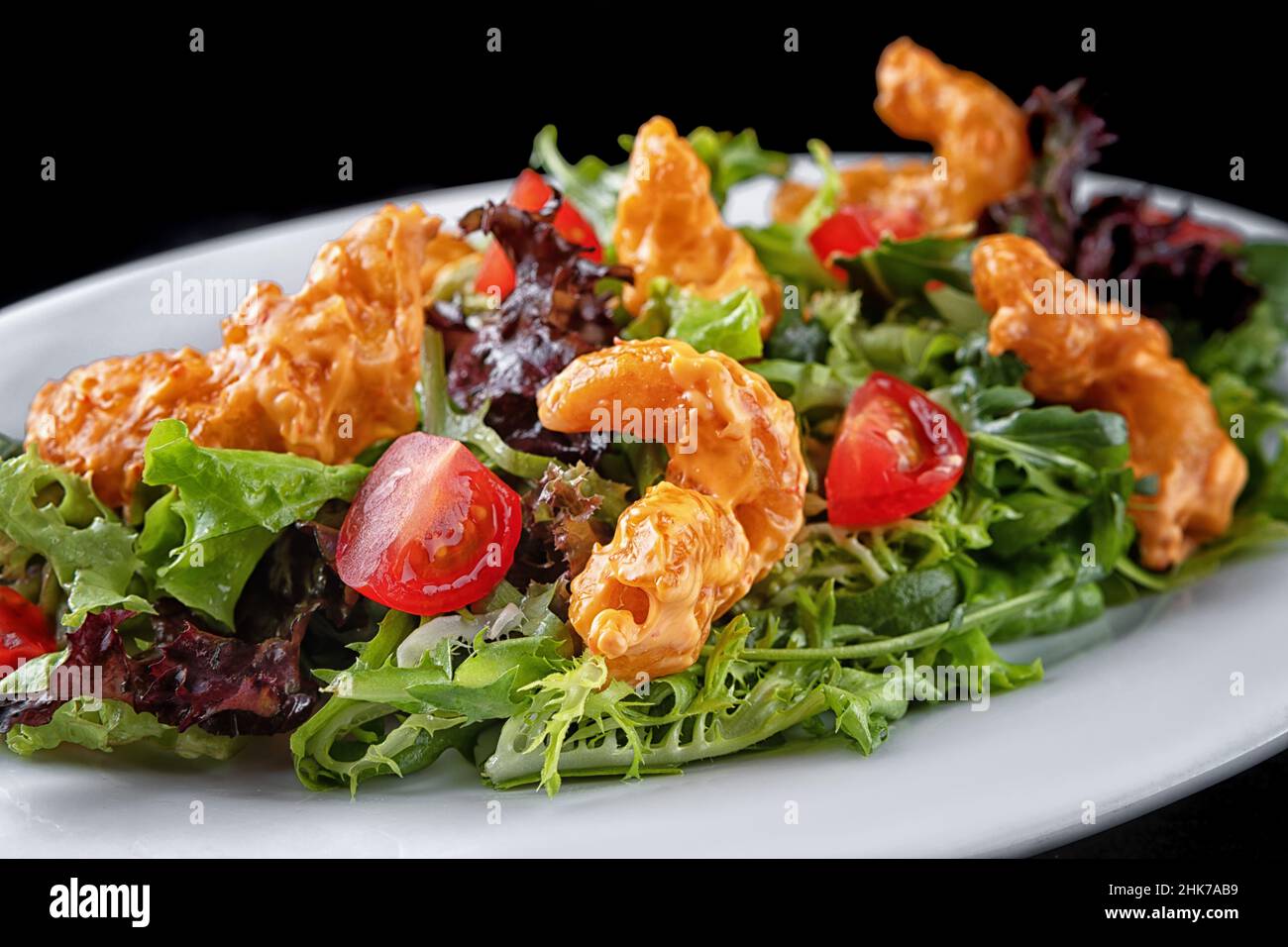 Salad with shrimp in batter, herbs and tomatoes on a plate Stock Photo