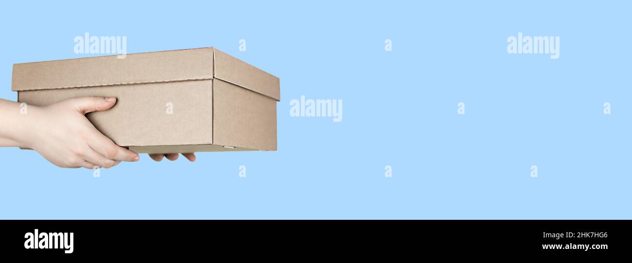 Large cardboard box in hands on blue background Stock Photo