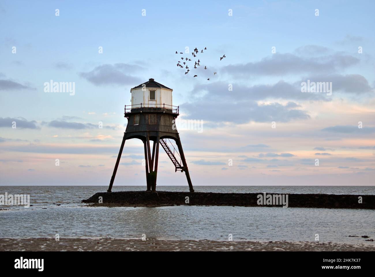A flock of seagulls fly above the Victorian Dovercourt lighthouse in the beautiful colourful evening sky. Harwich & Dovercourt, North Essex Coast, UK Stock Photo