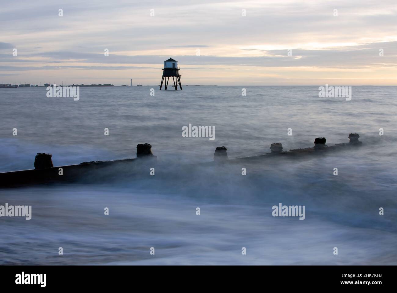 Waves break on the beach during sunrise at the historic Dovercourt Lighthouse, Harwich & Dovercourt Bay, Essex, UK Stock Photo