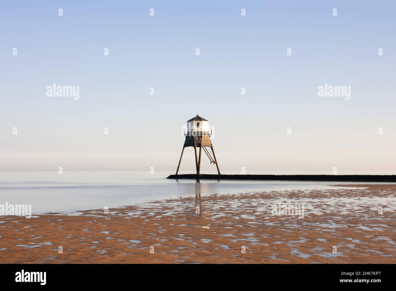A clear hazy day  at low tide by the causeway and historic Dovercourt Lighthouse, Harwich & Dovercourt Bay, Essex, UK Stock Photo