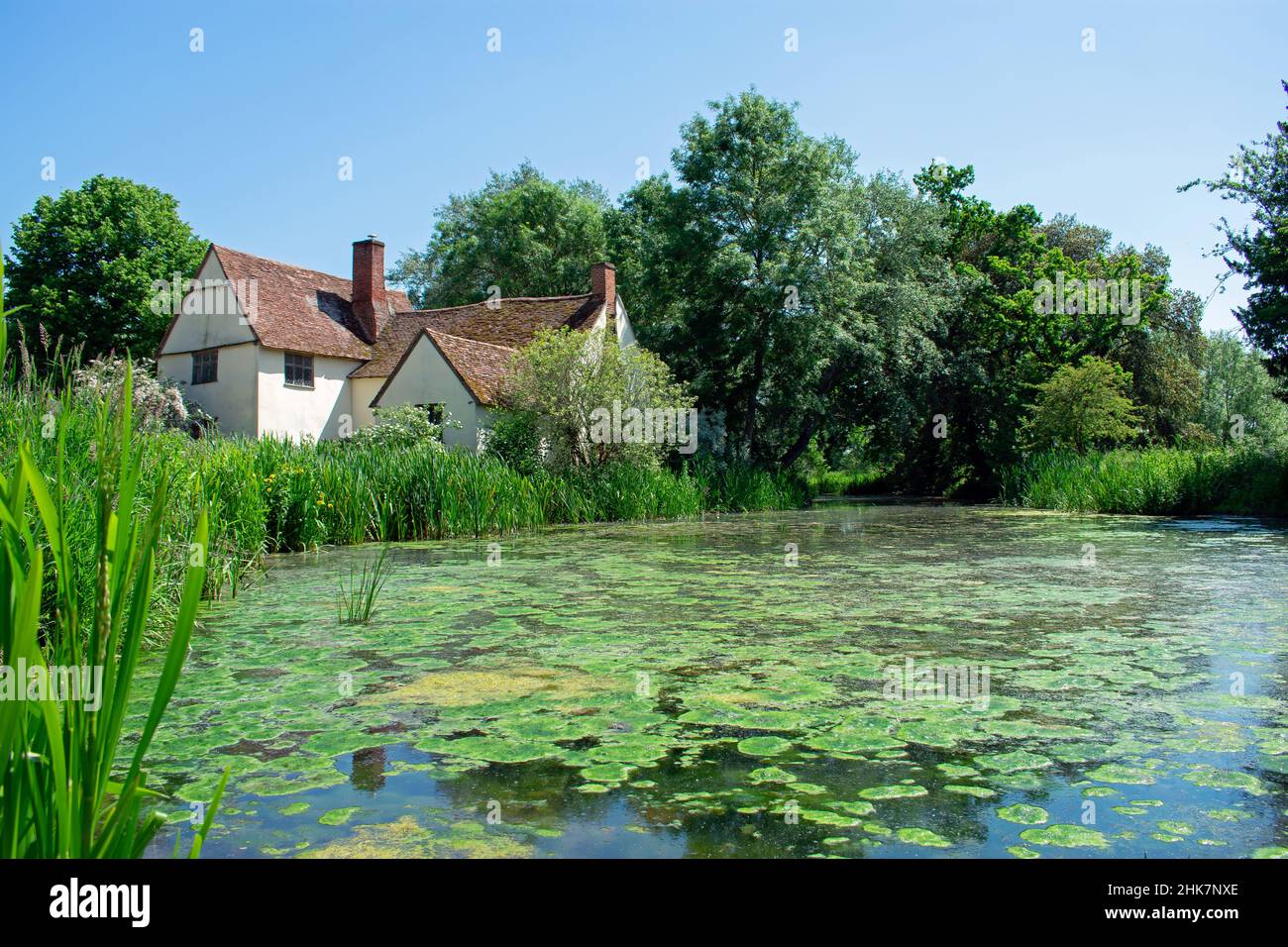Willy Lott's Cottage in Flatford, Operated by the National Trust in Suffolk, England.  The plant filled River Stour sits outside of the rural cottage. Stock Photo