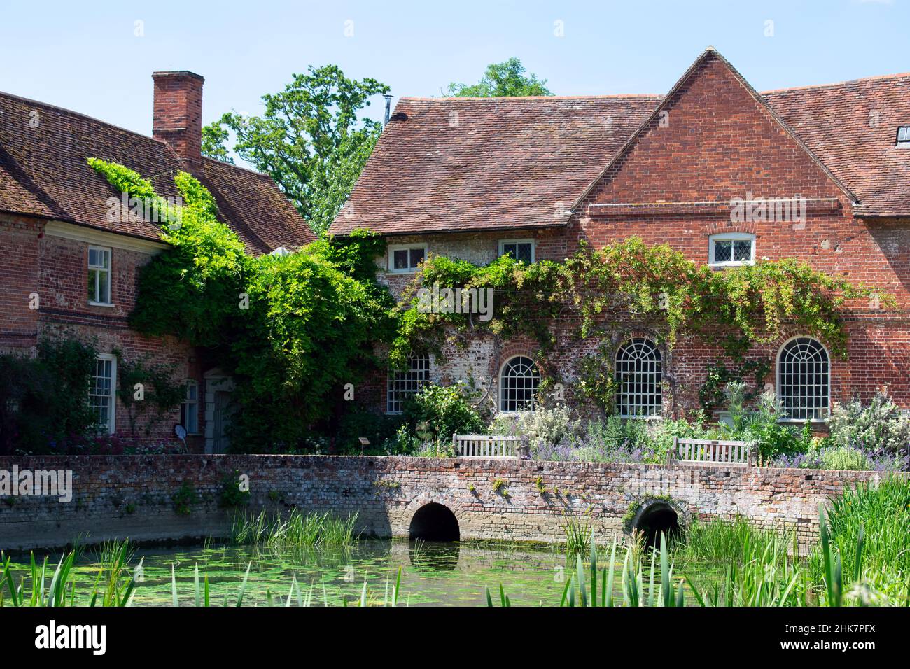 Flatford Mill and the Miller's Cottage, Operated by the National Trust in Suffolk, England. Foliage and vines climb the brickwork of the listed mill. Stock Photo