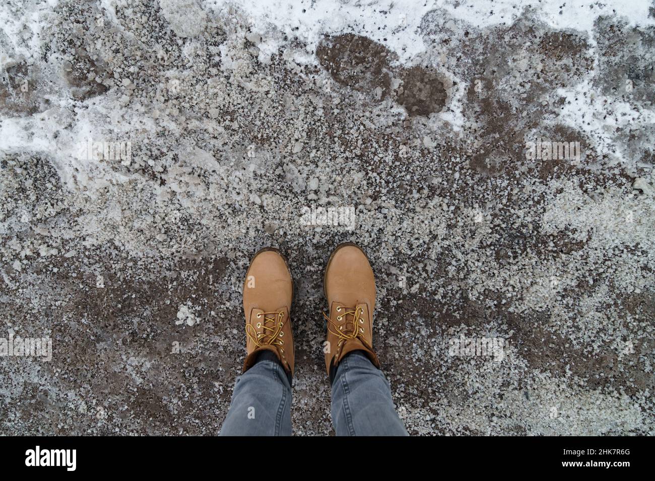 Antiicing chemicals in winter season. Top view of winter boots and road strewn with technical