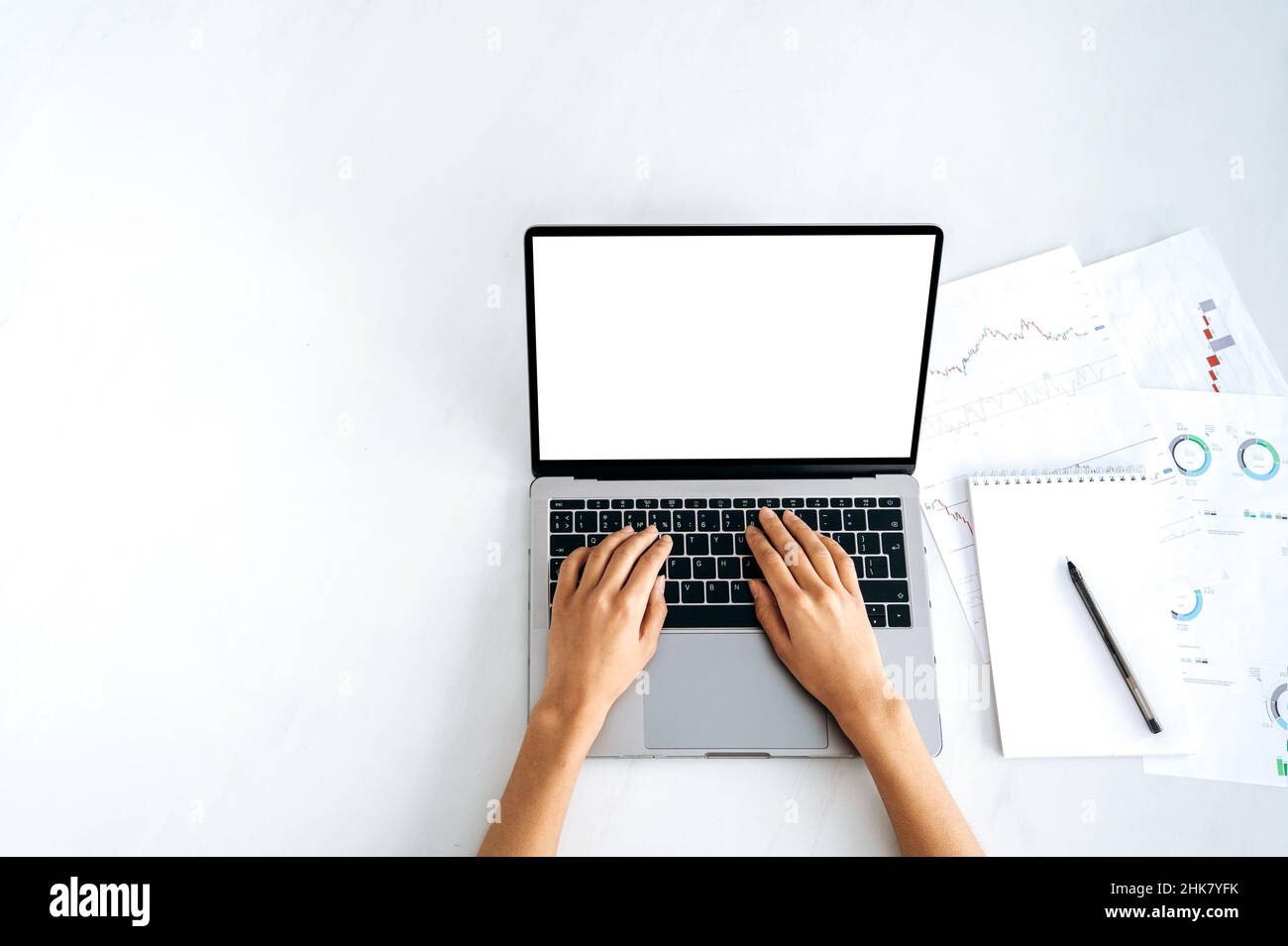 Laptop with white blank screen, mockup for announcement, advertising. Top view, female hands lie on a laptop keyboard with a blank white screen, a girl typing text,browsing information on the Internet Stock Photo