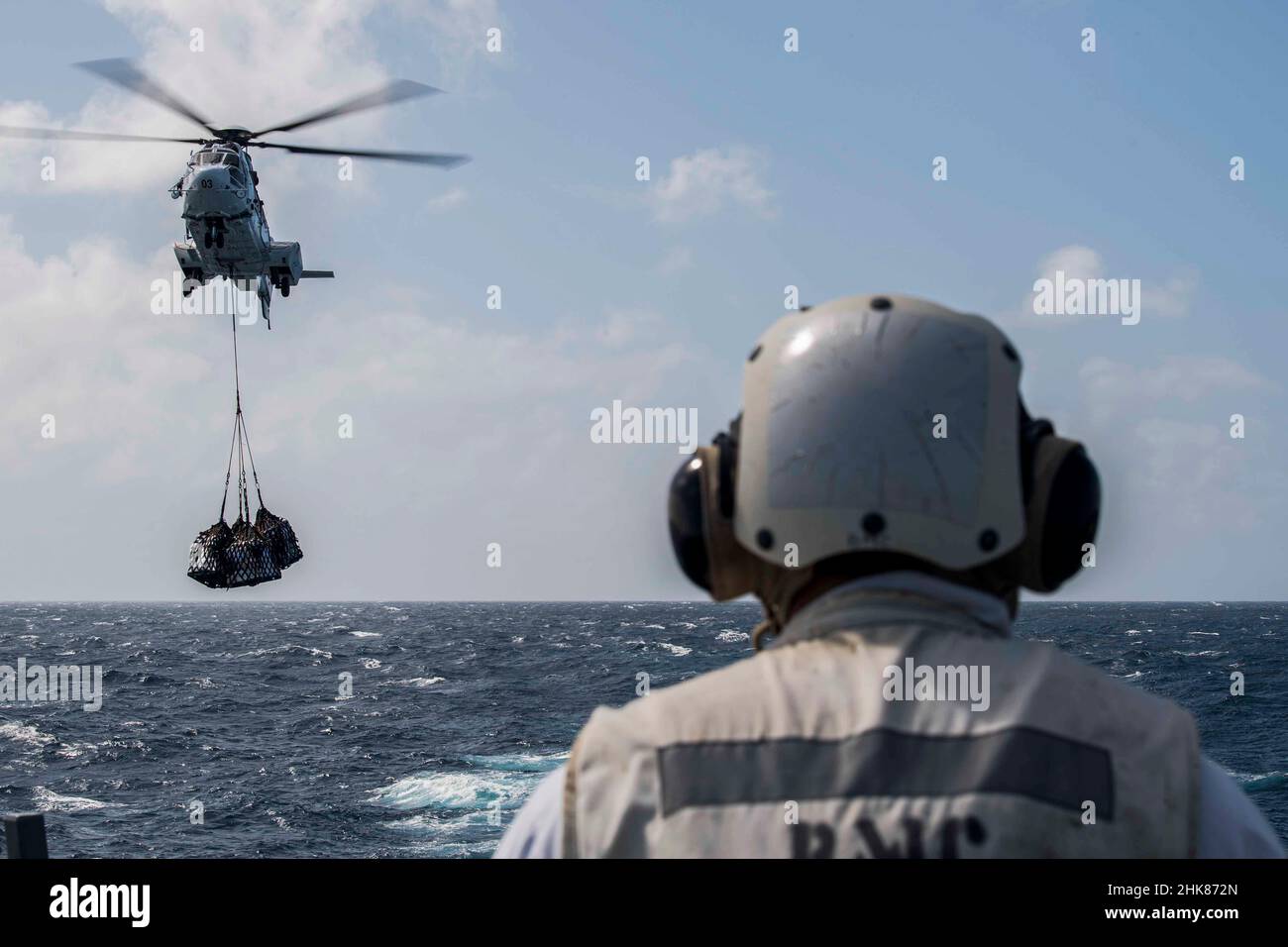 SOUTH CHINA SEA (Jan. 31, 2022) Chief Boatswain’s Mate Ryan Flores, from Olongapo City, Philippines, monitors an AS332 Super Puma helicopter assigned to the Military Sealift Command fleet replenishment oiler USNS Matthew Perry (T-AKE 9), during a vertical replenishment-at-sea with the Arleigh Burke-class guided-missile destroyer USS Gridley (DDG 101). Abraham Lincoln Strike Group is on a scheduled deployment in the U.S. 7th Fleet area of operations to enhance interoperability through alliances and partnerships while serving as a ready-response force in support of a free and open Indo-Pacific r Stock Photo