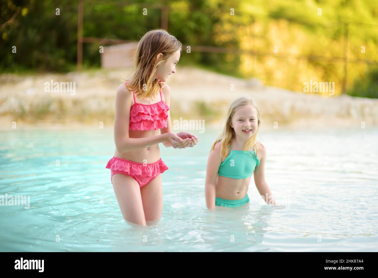 Two young sisters bathing in natural swimming pool in Bagno Vignoni, with  thermal spring water and calcium carbonate deposits, which form white  concre Stock Photo - Alamy