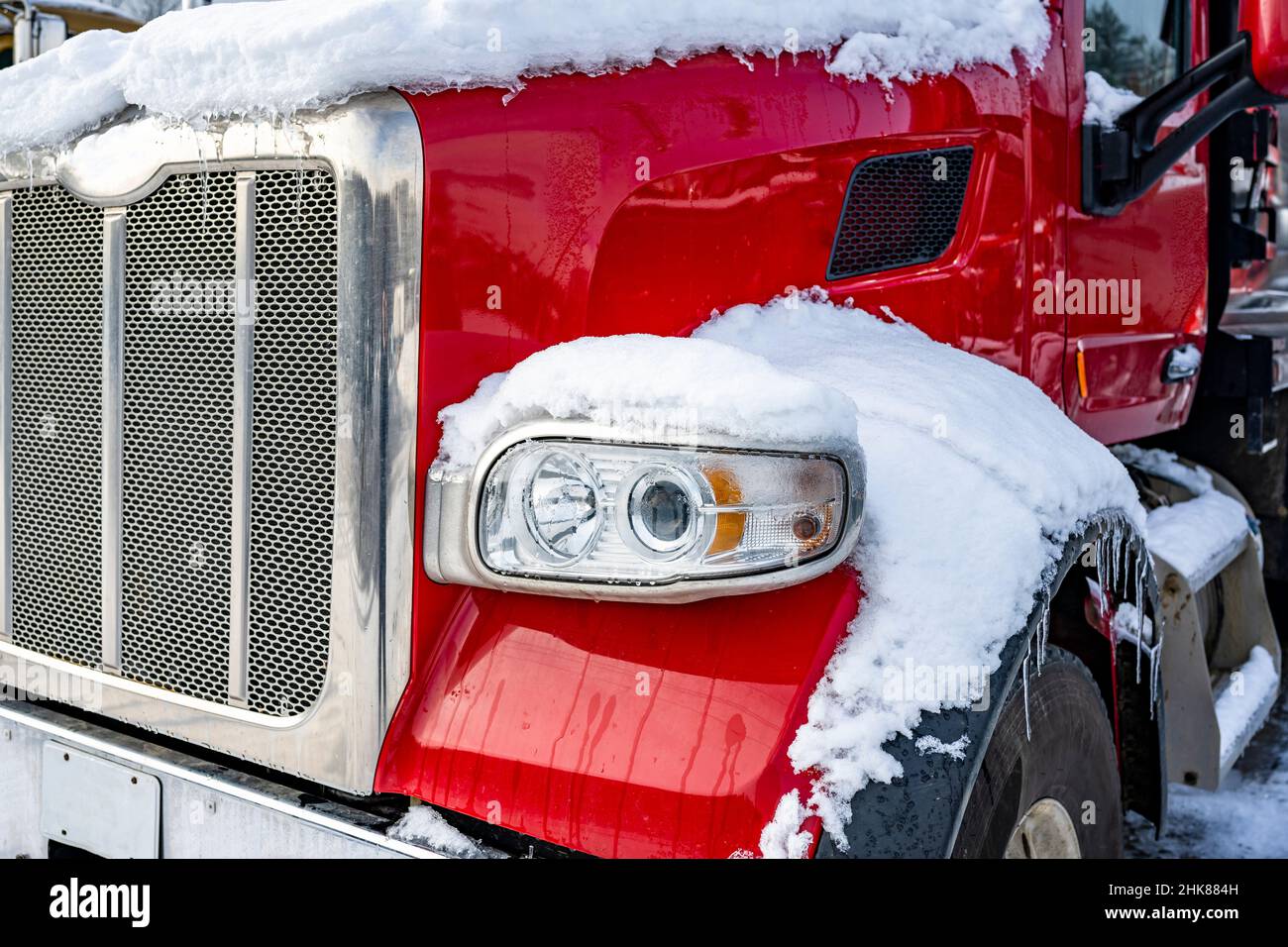 Red big rig classic semi truck tractor with chrome grille and accessories standing for truck driver rest on the industrial truck stop parking lot cove Stock Photo