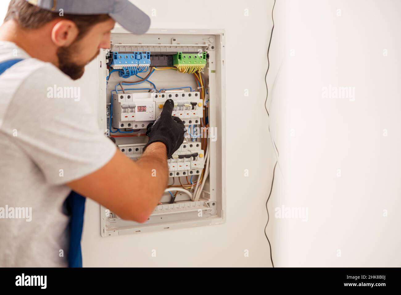 Electrical technician in uniform looking focused while working in a switchboard with fuses Stock Photo