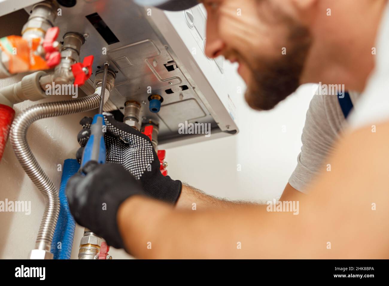 Closeup of plumber using screwdriver while installing new steel hot water central heating system in apartment Stock Photo