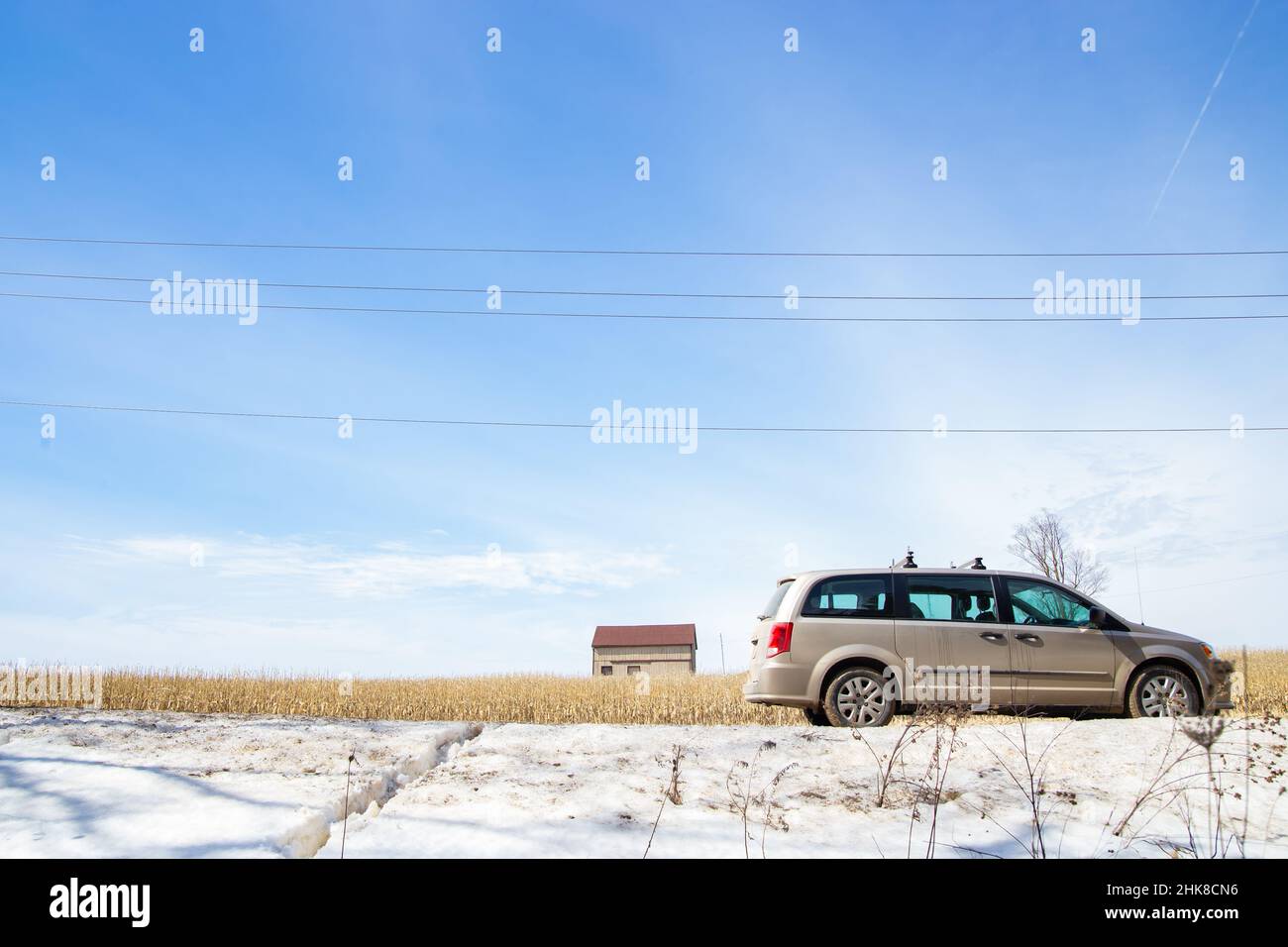 Grey car and wooden shed in snow field and silver grass under blue sky in Canada Stock Photo