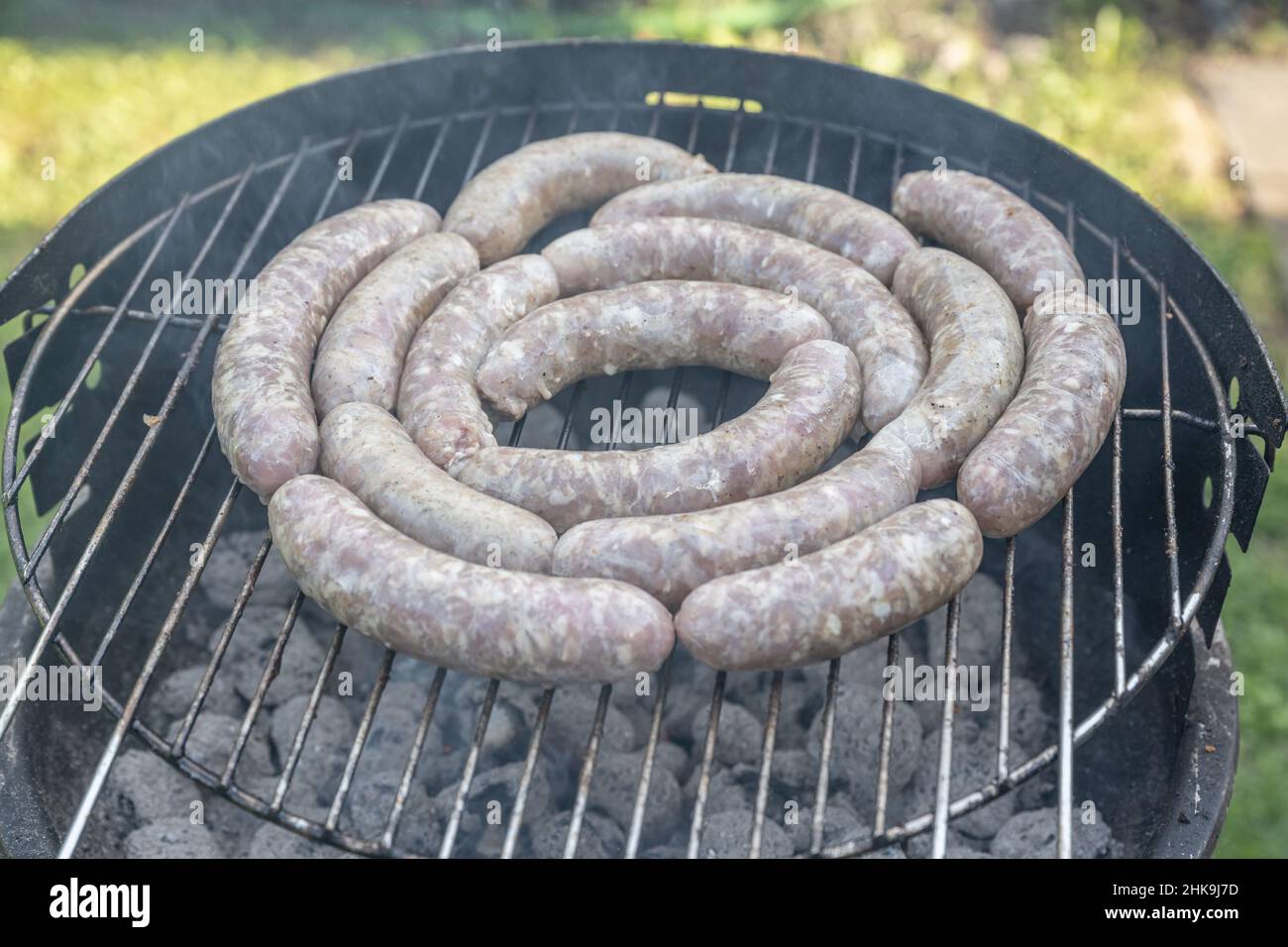 Barbecue grill bbq on coal charcoal grill with raw bratwurst sausages meat delicious summer meal. Stock Photo